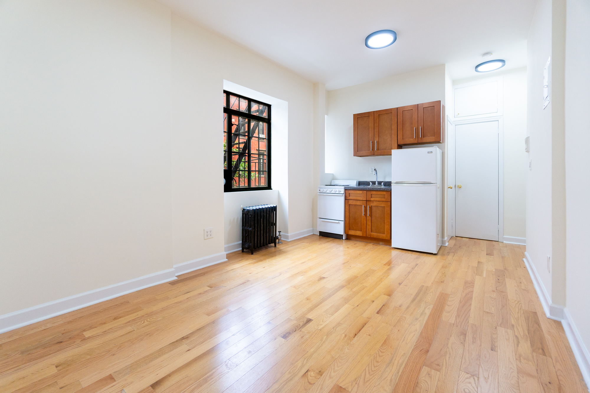 189 West 10th Street, Unit 2E Manhattan, NY 10014 - Photo 2 of 5 an empty room with wooden floor and windows