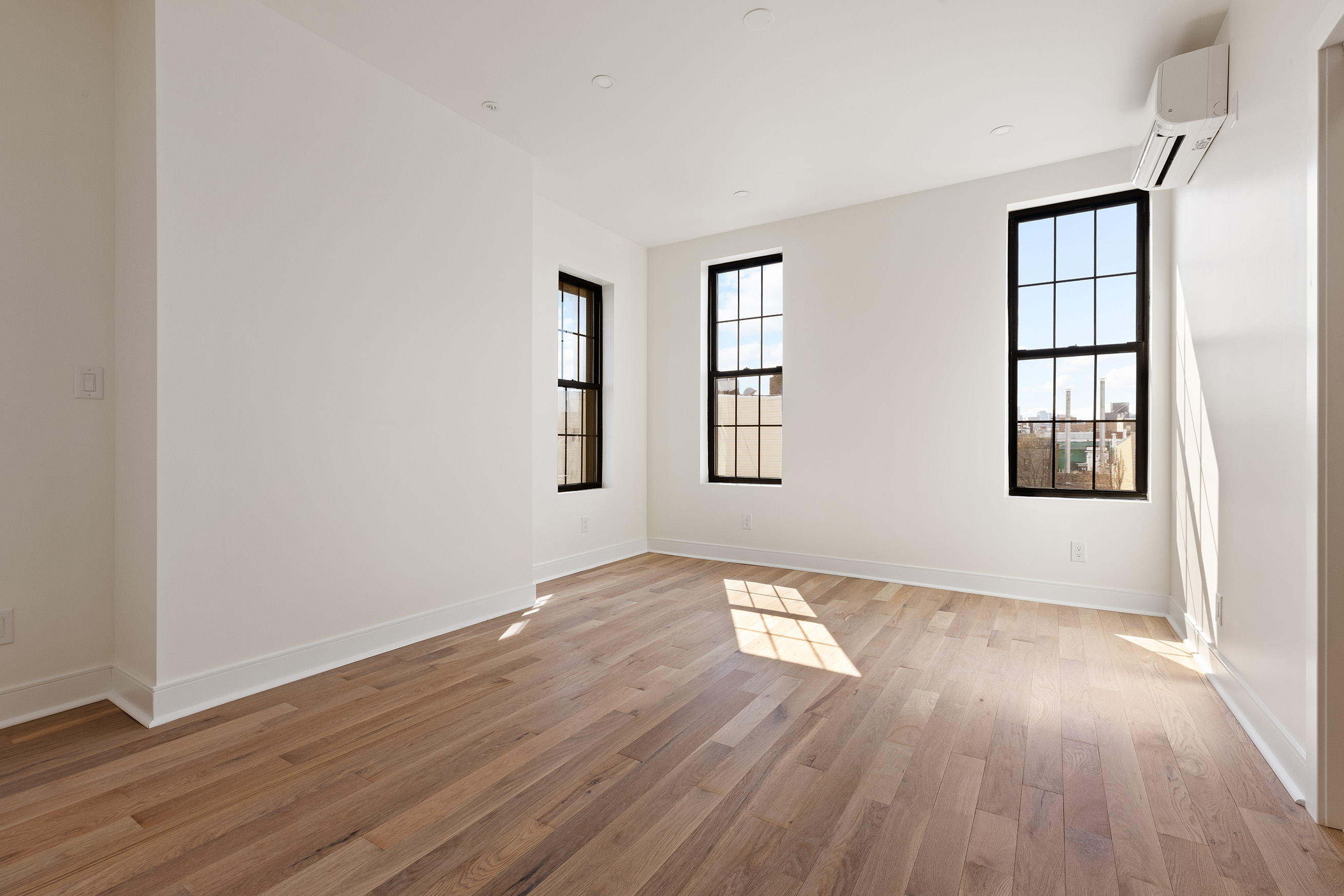 152 North 10th Street, Unit 1L Brooklyn, NY 11249 - Photo 6 of 18 an empty room with wooden floor and windows