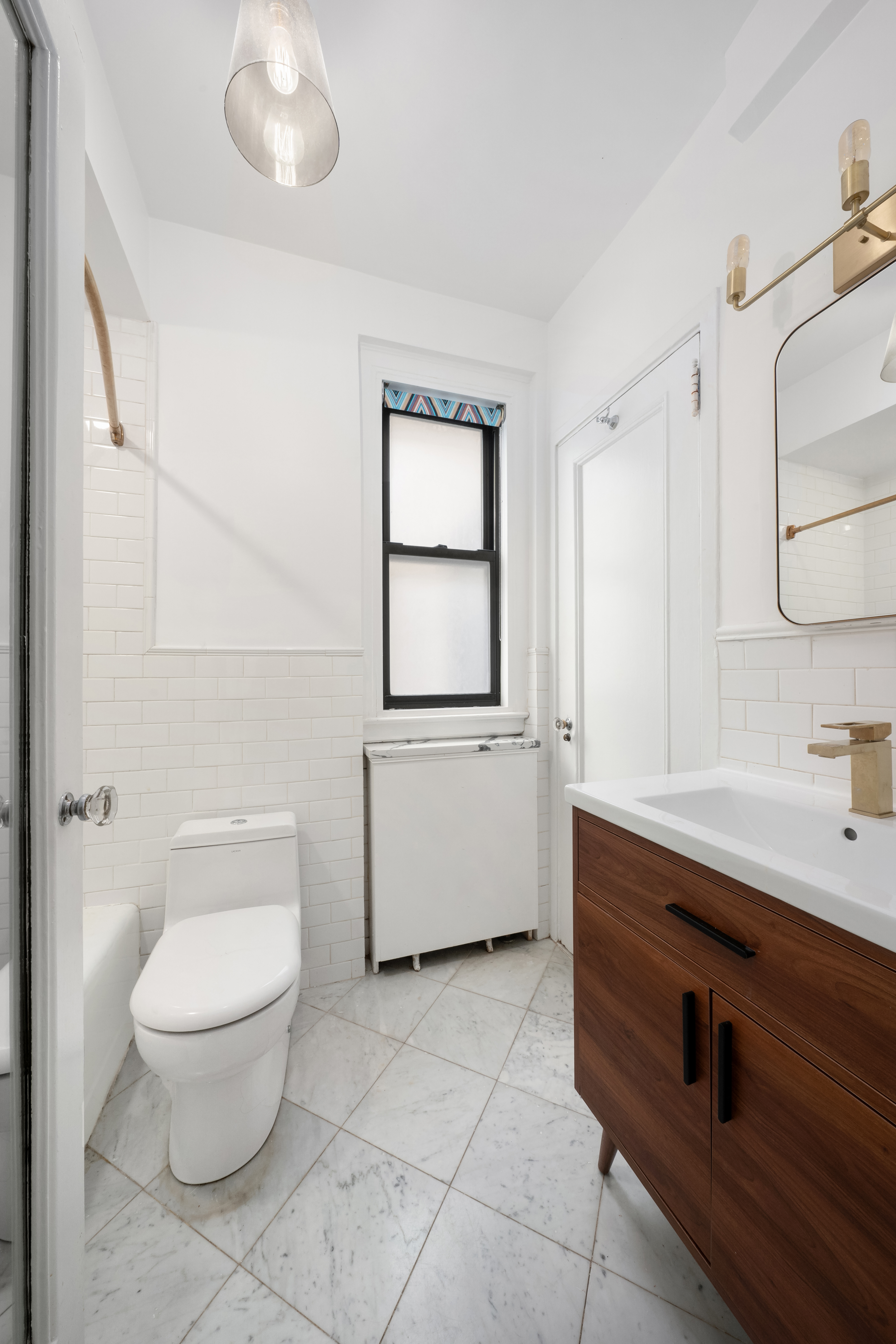 150 West 55th Street, Unit 5D Manhattan, NY 10019 - Photo 9 of 12 a bathroom with a toilet a sink and mirror