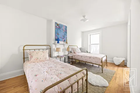 a bedroom with two beds and wooden floor