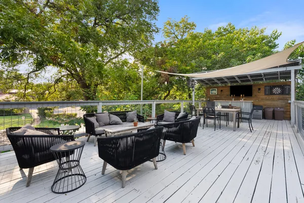 a roof deck with table and chairs potted plants with wooden floor and fence