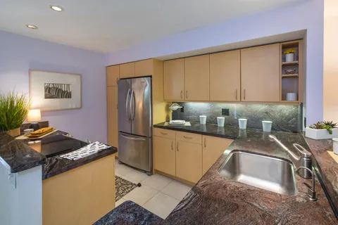a kitchen with granite countertop a sink stove and refrigerator