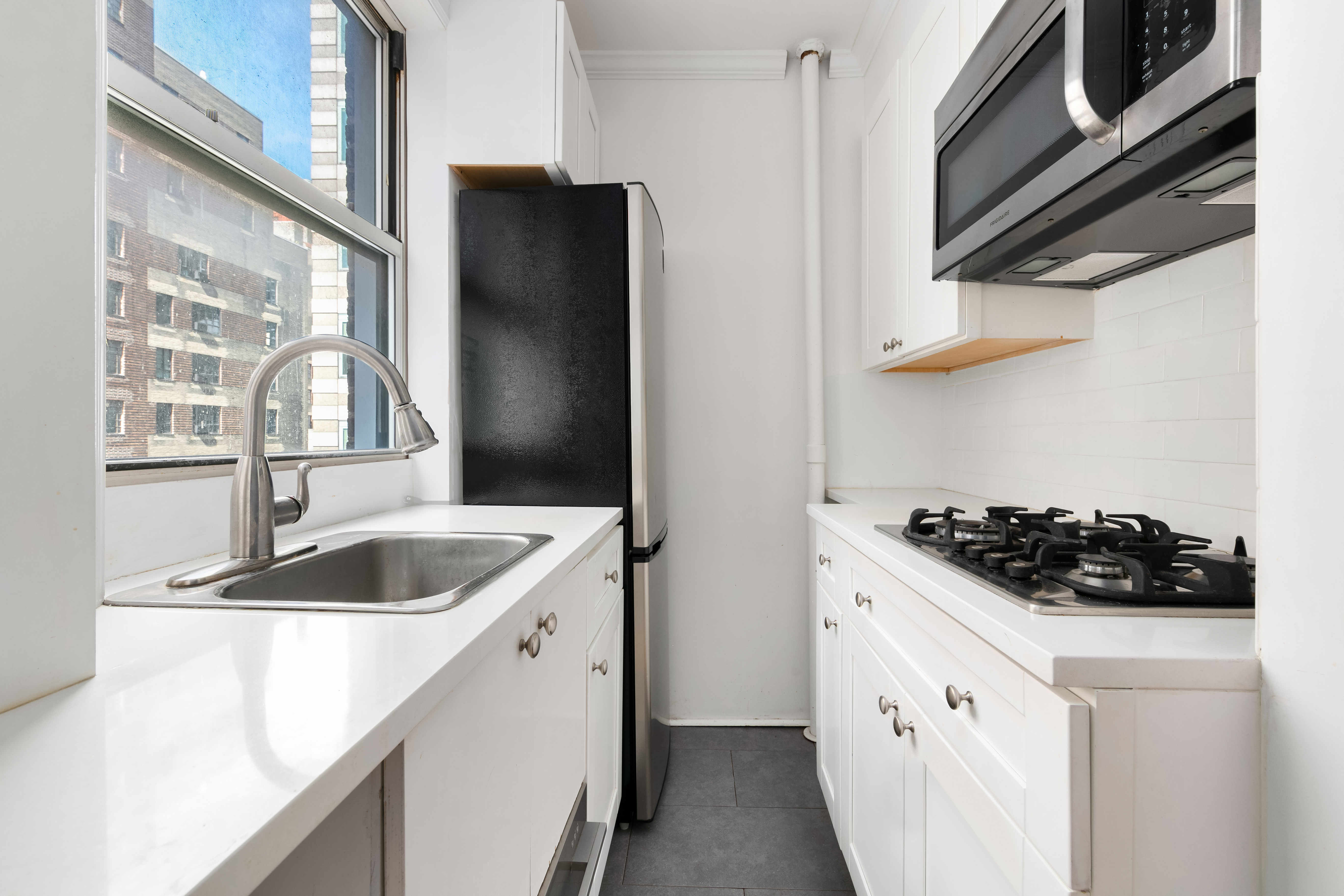 333 East 43rd Street, Unit 910 Manhattan, NY 10017 - Photo 2 of 13 a kitchen with stainless steel appliances granite countertop a sink and a refrigerator
