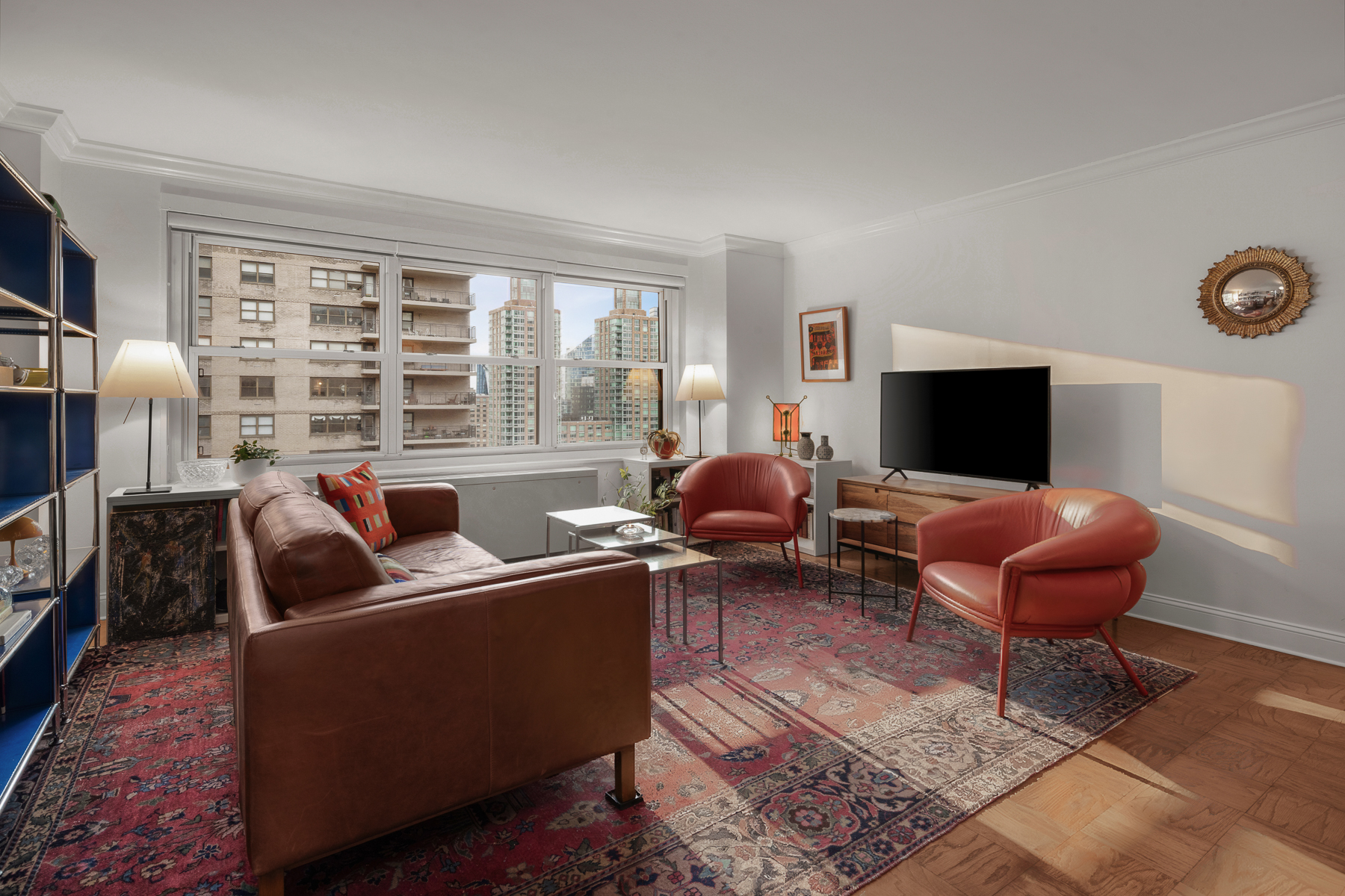 150 West End Avenue, Unit 24S Manhattan, NY 10023 - Photo 2 of 14 a living room with furniture a flat screen tv and a fireplace