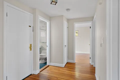 a view of an empty room with wooden floor and a bathroom
