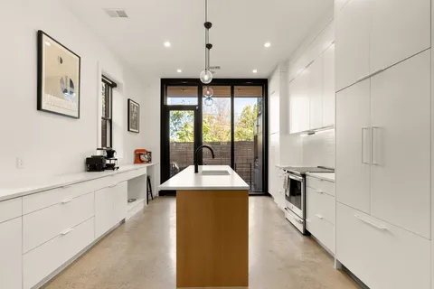 a large kitchen with granite countertop a large counter top a sink stainless steel appliances and cabinets