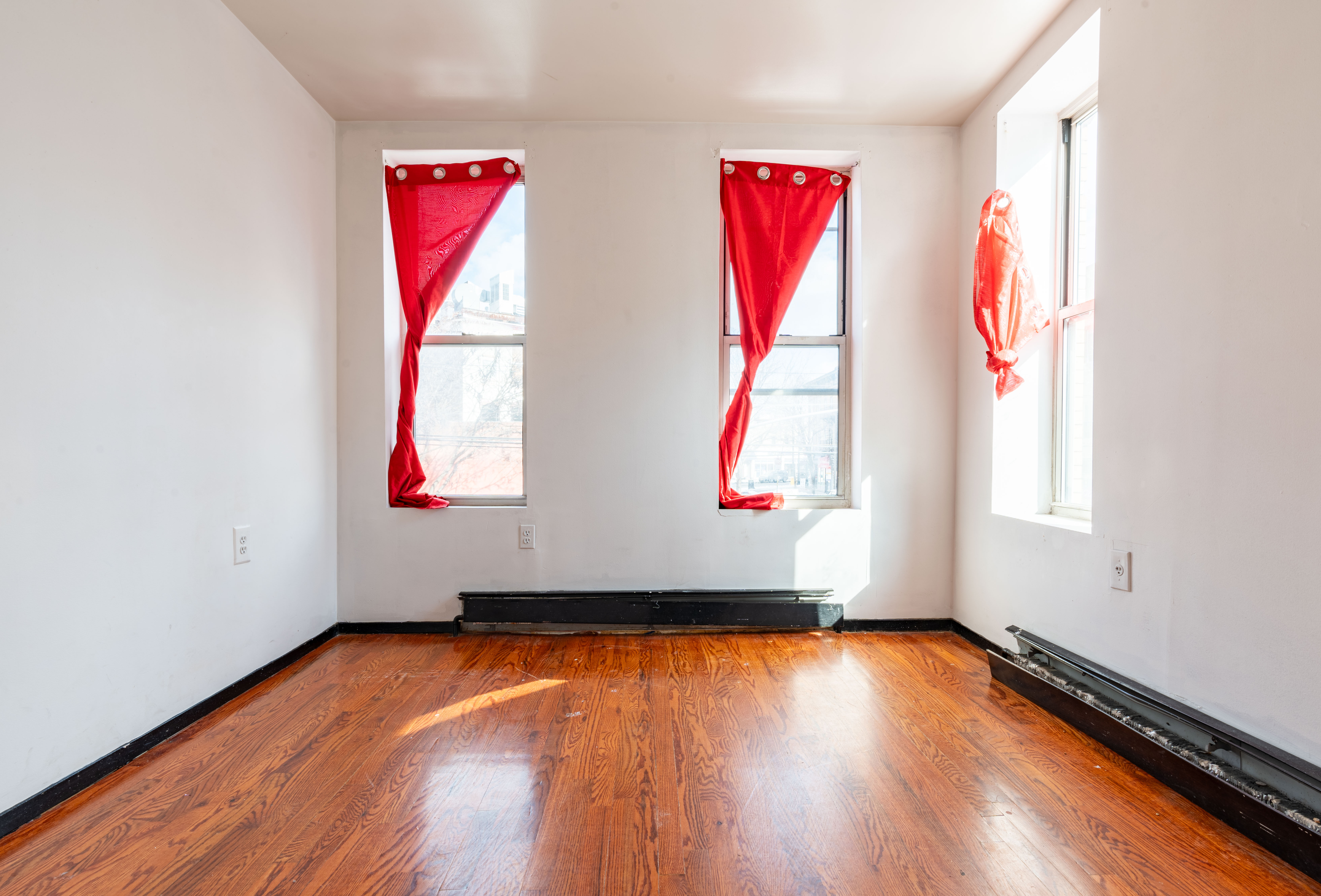 936 Seneca Avenue Queens, NY 11385 - Photo 11 of 12 a room with wooden floor and windows