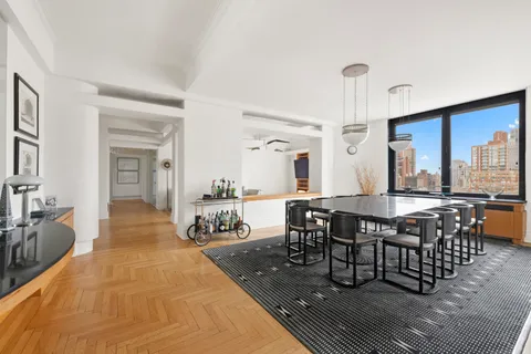 a dining hall with couches a dining table and chairs with wooden floor