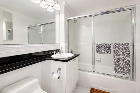a bathroom with a granite countertop sink a mirror and shower