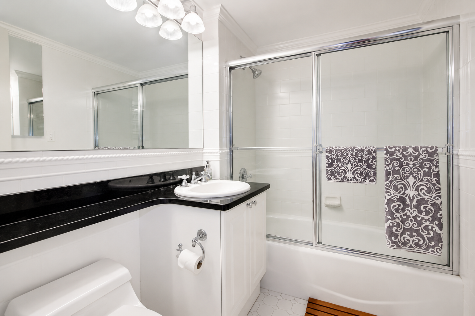 404 East 76th Street, Unit 6B Manhattan, NY 10021 - Photo 5 of 7 a bathroom with a granite countertop sink a mirror and shower