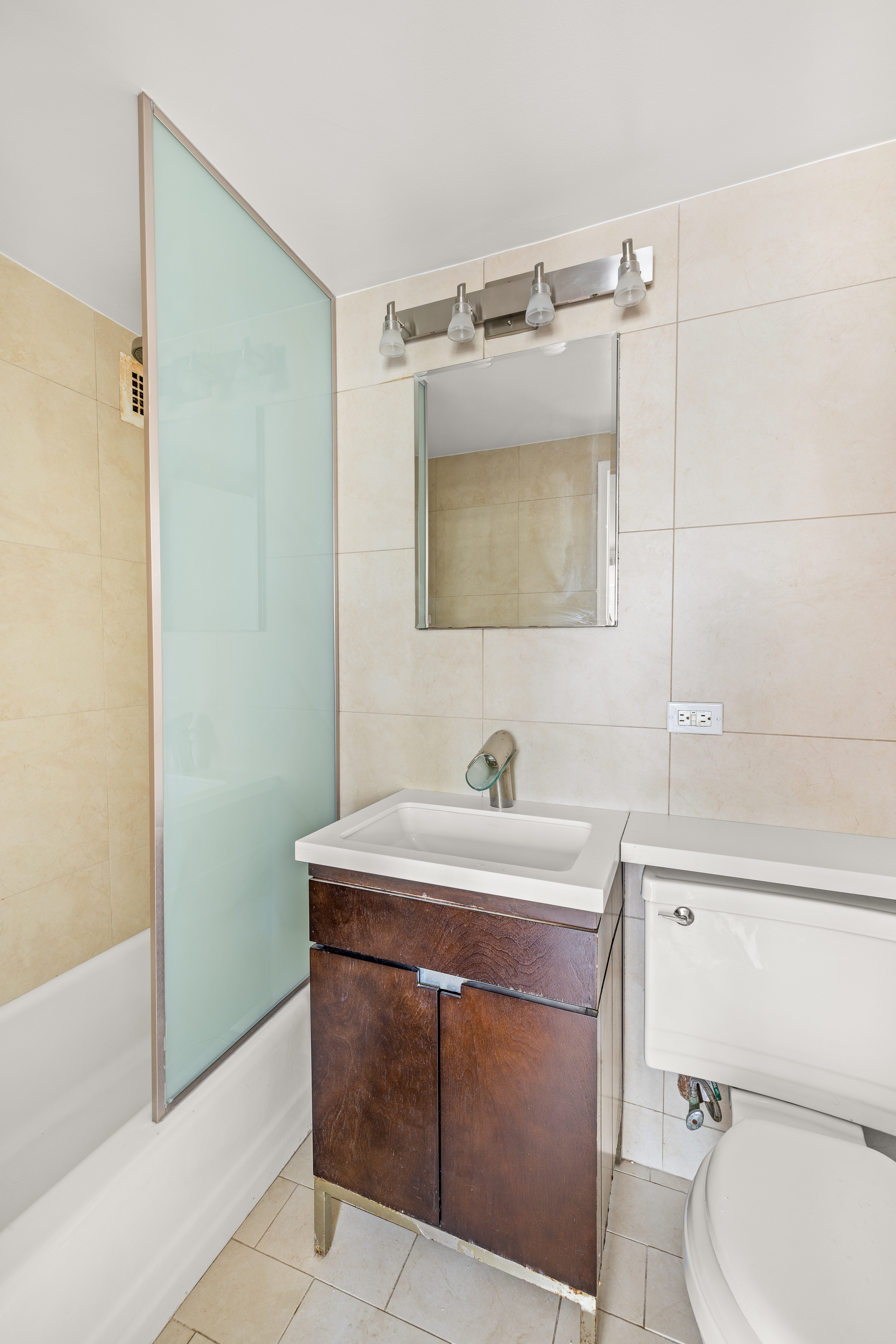 16 West 16th Street, Unit 14NN Manhattan, NY 10011 - Photo 5 of 10 a bathroom with a sink toilet vanity and tub