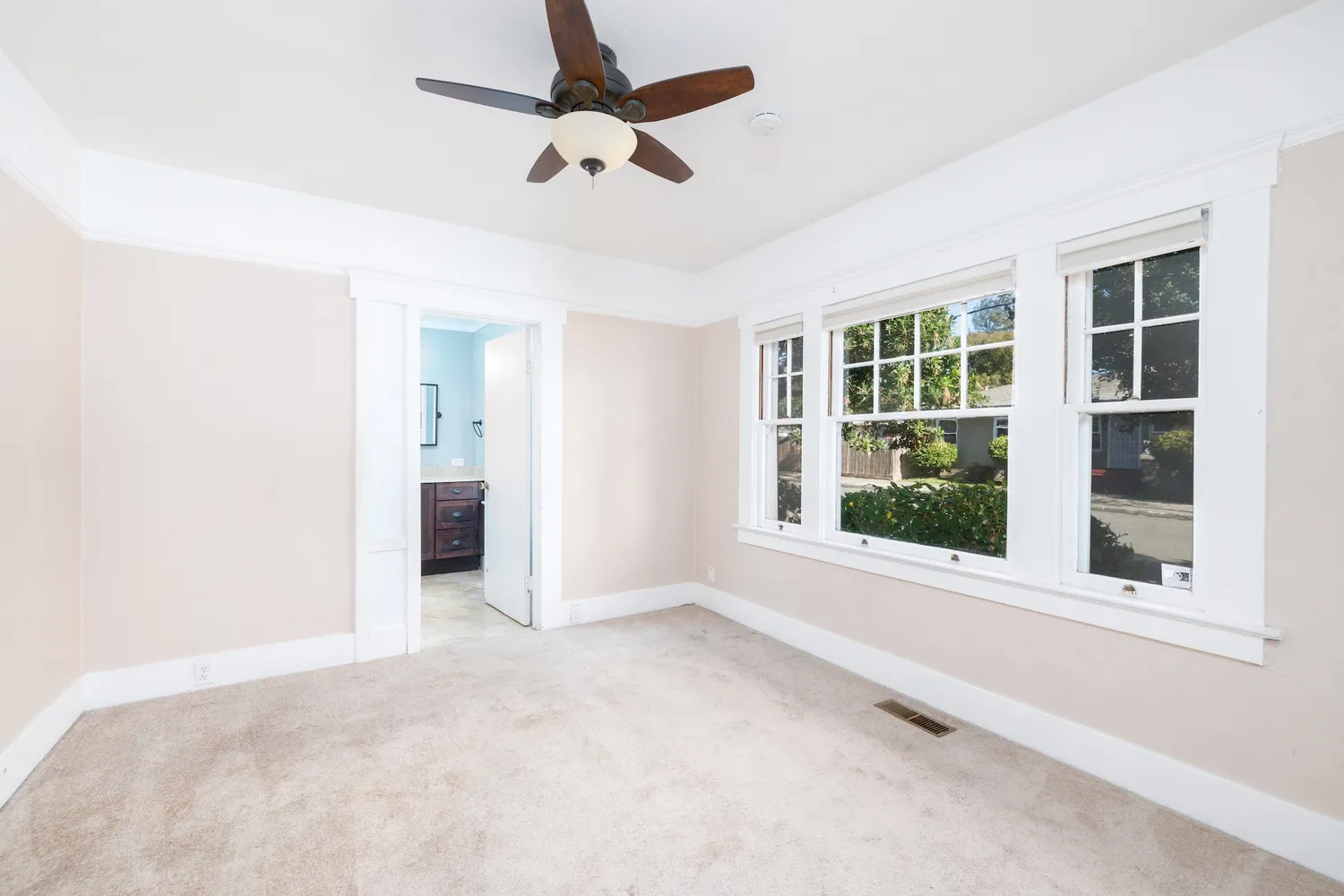 an empty room with windows and ceiling fan