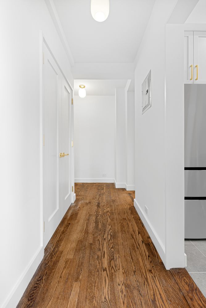 a view of a hallway with wooden floor and a living room
