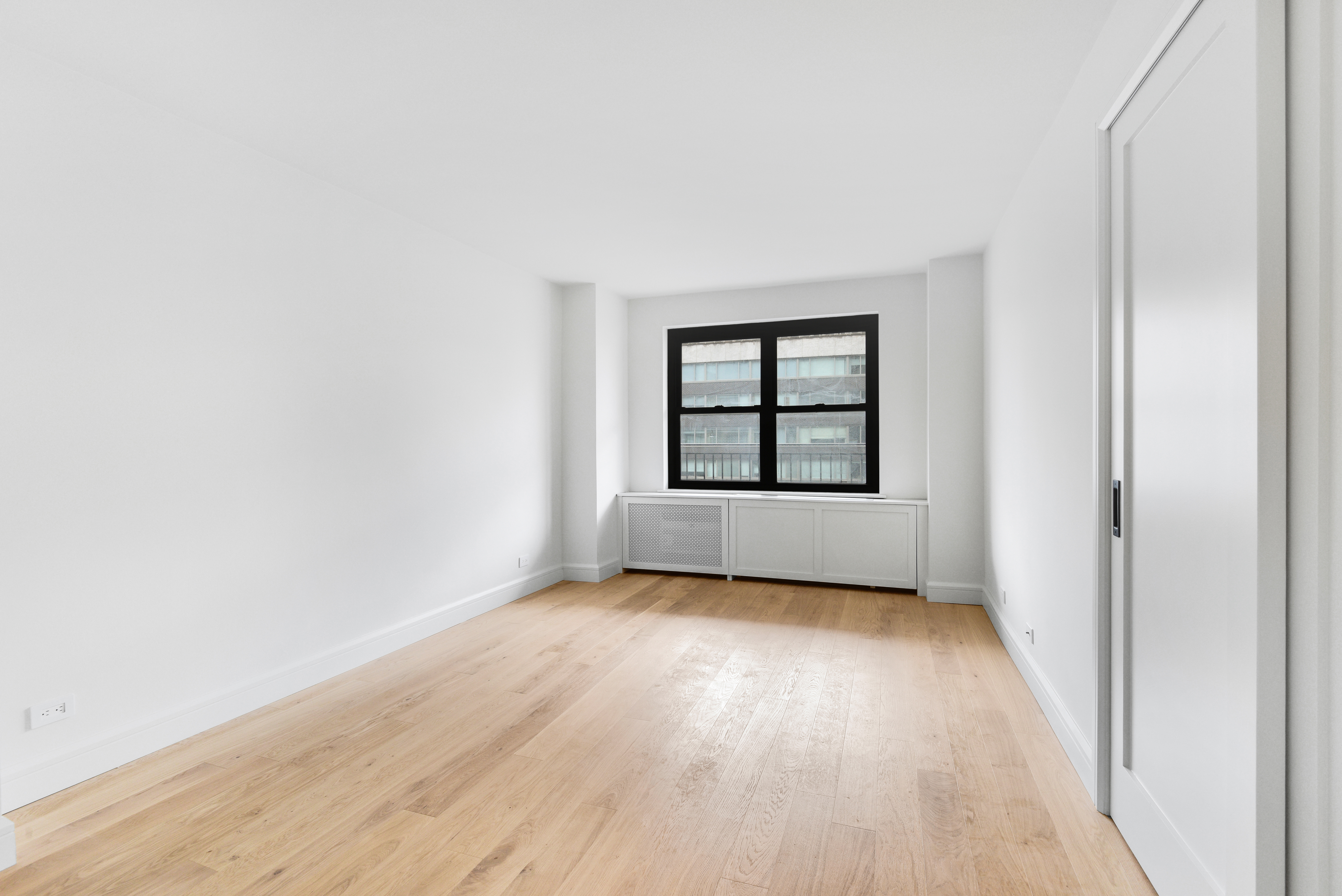 205 West End Avenue, Unit 15H Manhattan, NY 10023 - Photo 8 of 17 an empty room with wooden floor white walls and windows