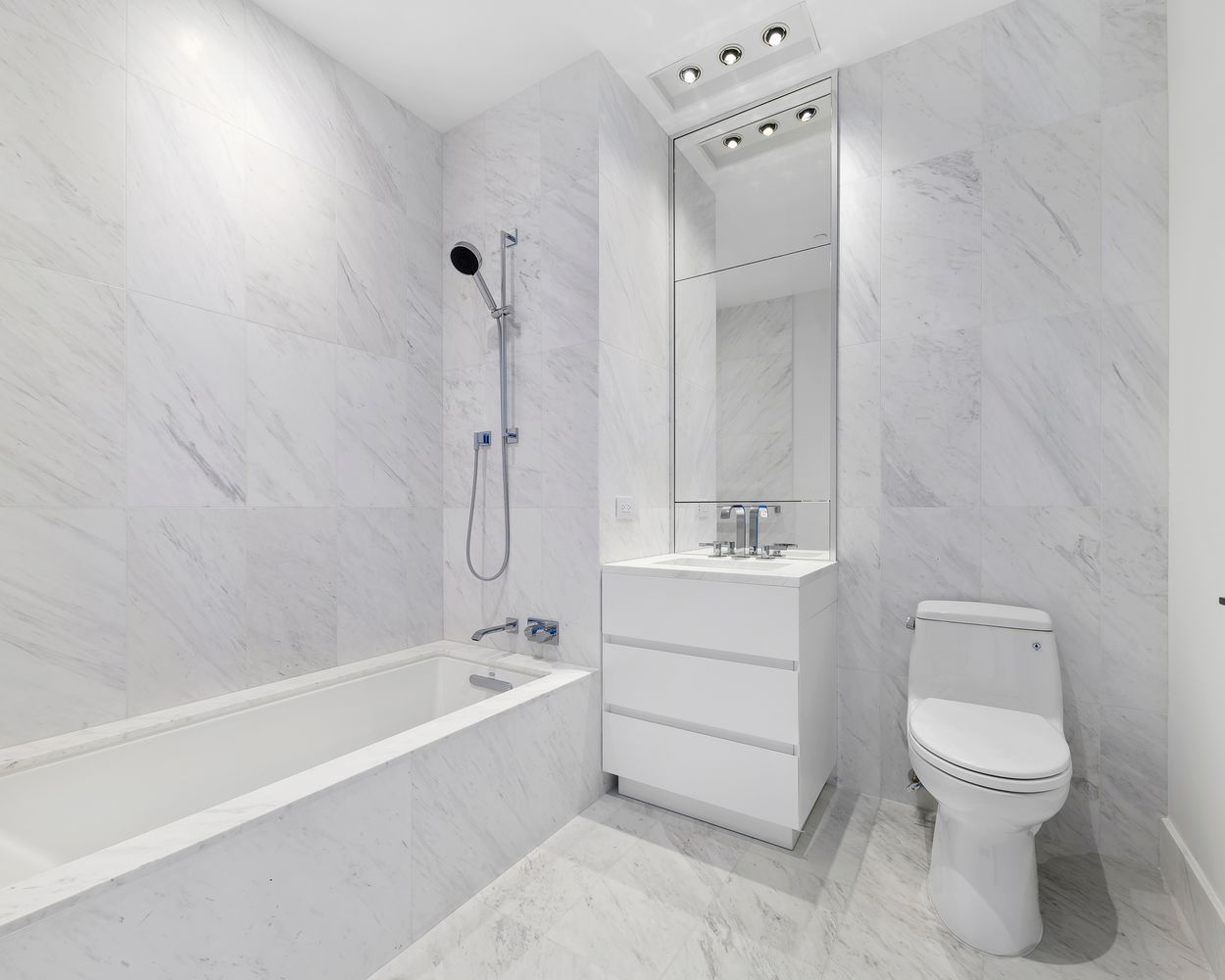 111 Murray Street, Unit 21A Manhattan, NY 10007 - Photo 6 of 14 a bathroom with a white toilet sitting next to a bathroom sink and a shower
