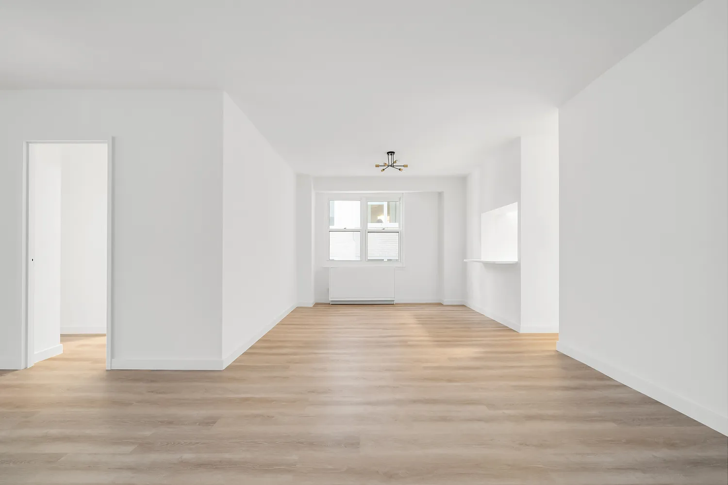 a view of an empty room with window and wooden floor