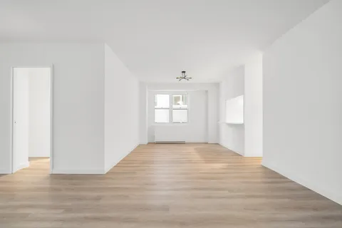 a view of an empty room with window and wooden floor