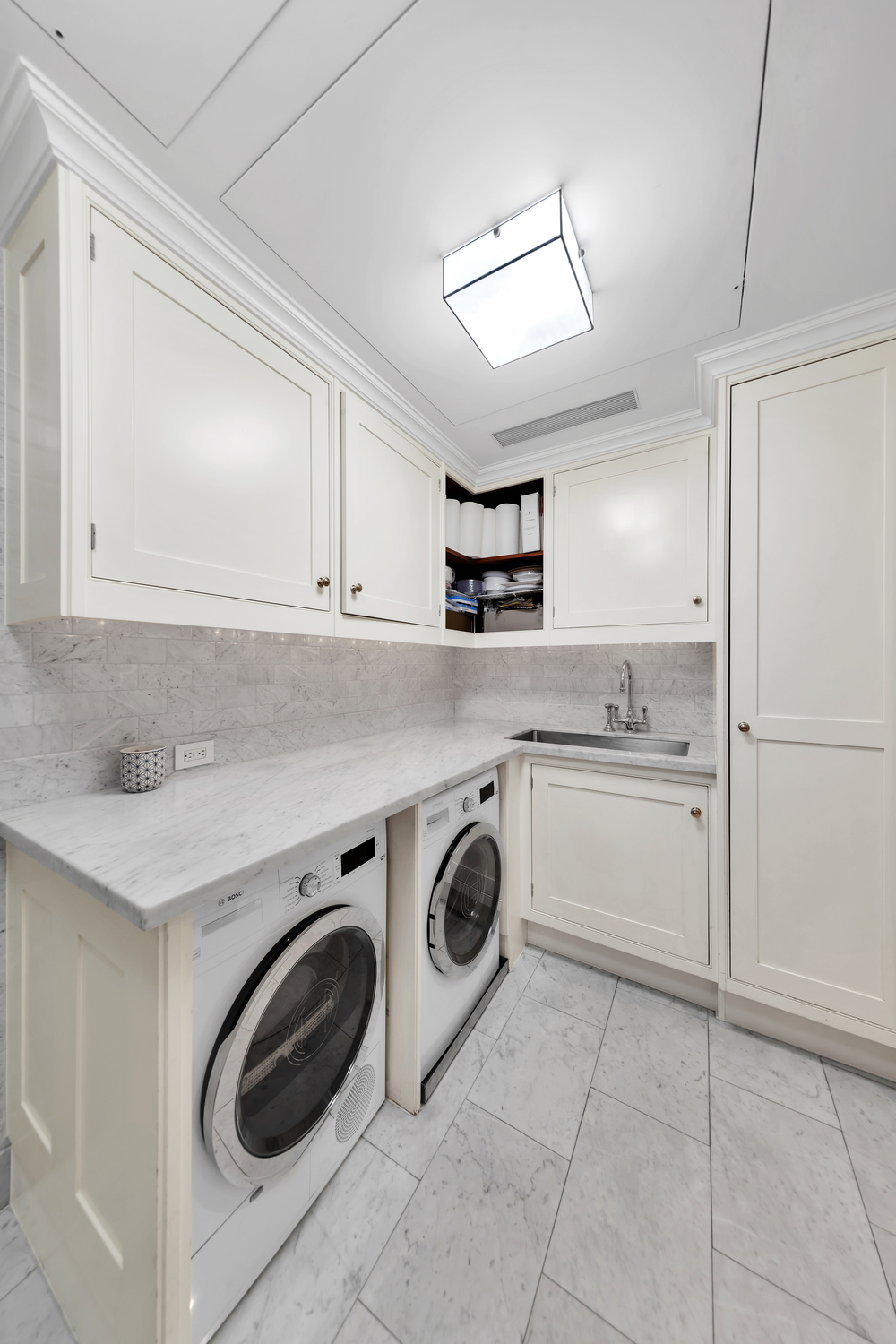 25 Central Park West, Unit 21J Manhattan, NY 10023 - Photo 31 of 37 a utility room with cabinets washer and dryer