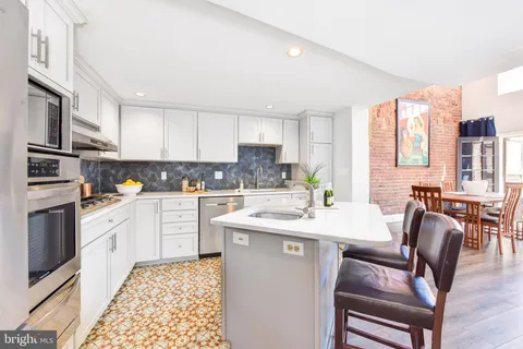 a kitchen with stainless steel appliances granite countertop a stove a sink dishwasher a stove a refrigerator with a dining table and chairs
