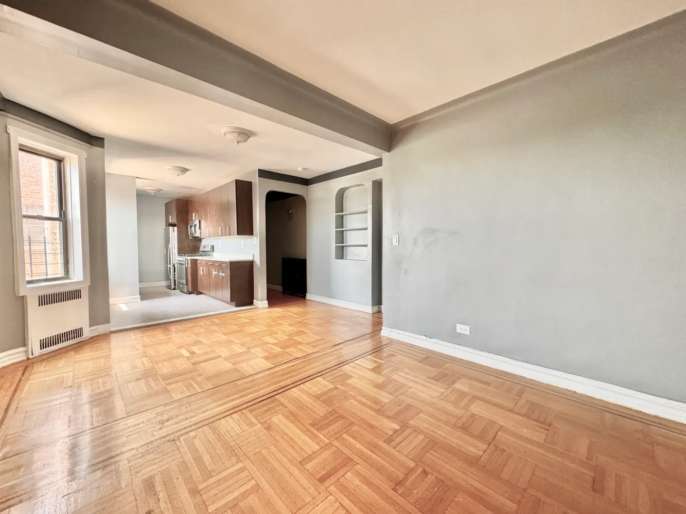 a view of a livingroom with wooden floor and a kitchen space