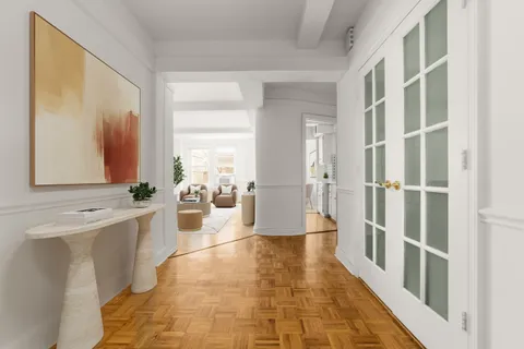 a hallway with white cabinets and wooden floor