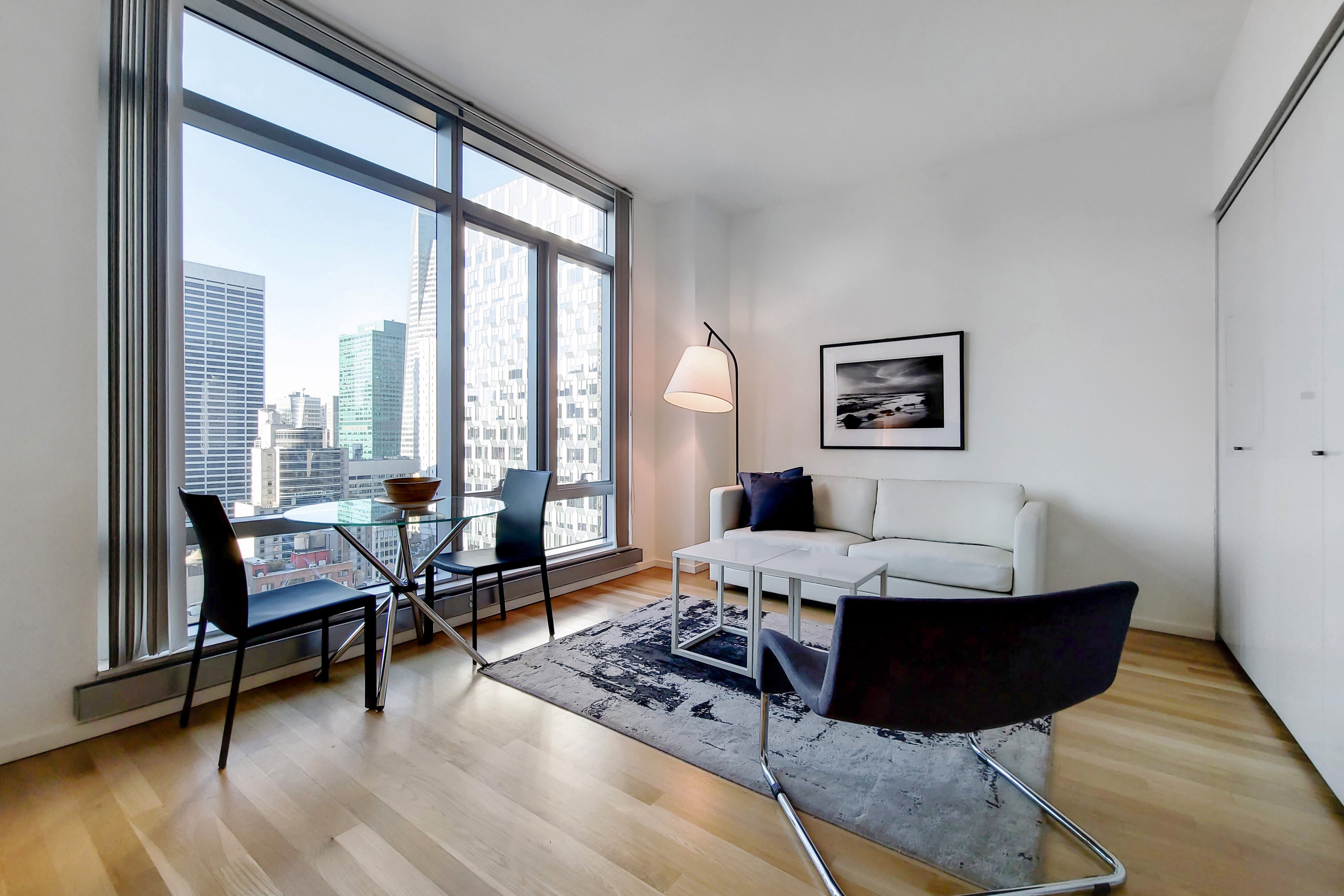18 West 48th Street, Unit 30D Manhattan, NY 10036 - Photo 1 of 11 a living room with furniture and floor to ceiling window