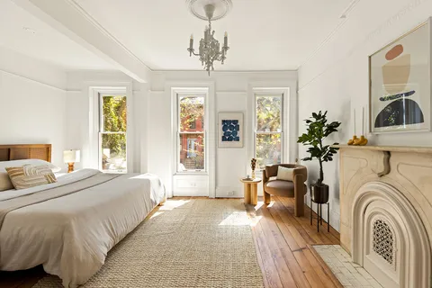 a spacious bedroom with a large bed a chandelier and windows