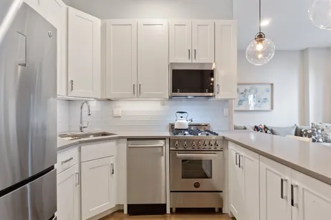 a kitchen with cabinets stainless steel appliances a sink and a stove