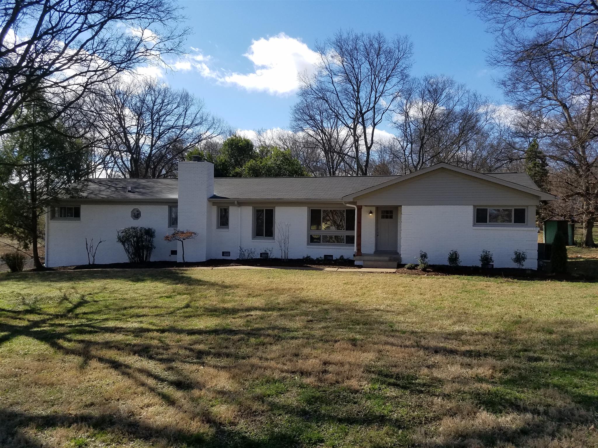 a front view of house with yard and trees in the background