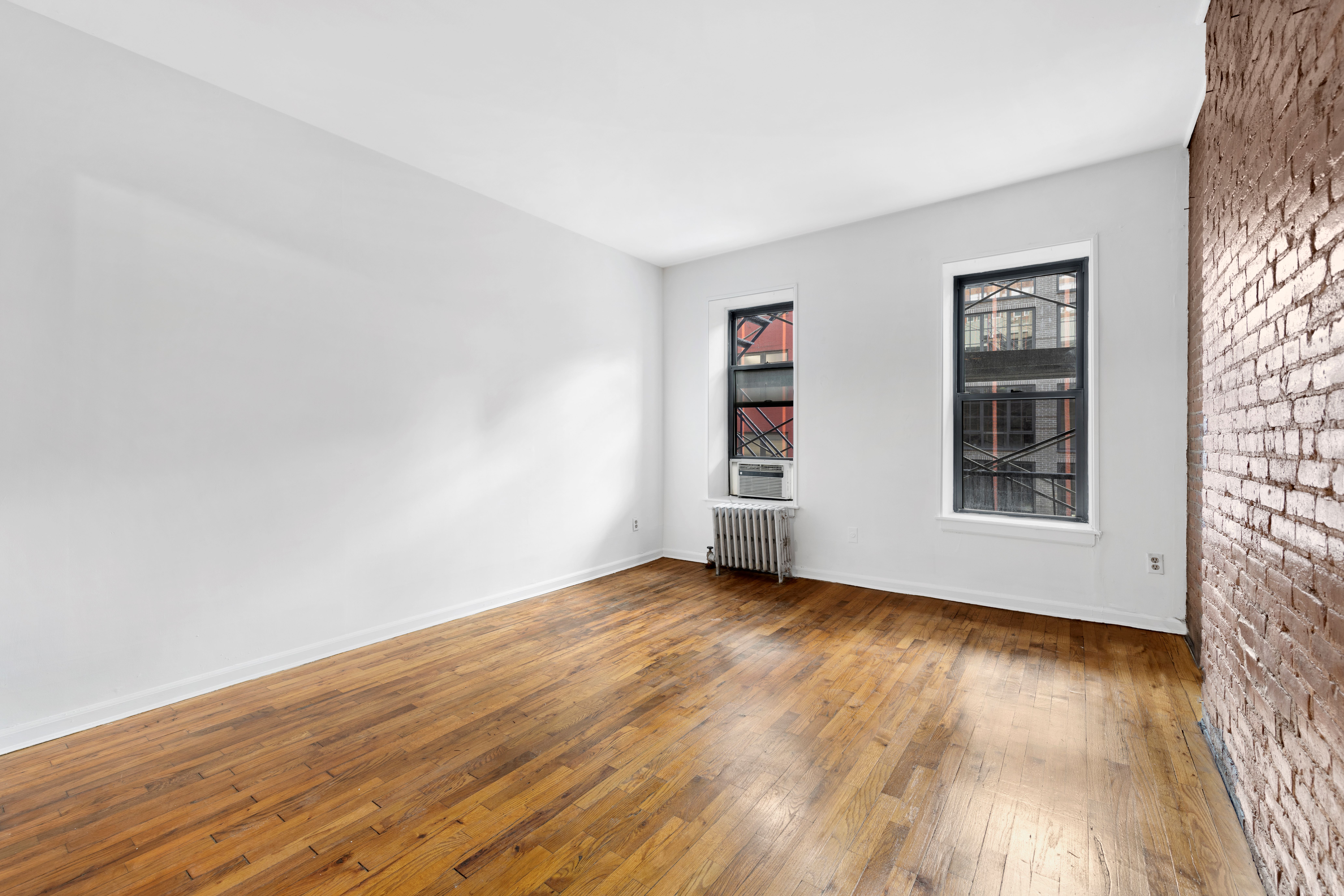 433 West 54th Street, Unit 1 Manhattan, NY 10019 - Photo 6 of 9 an empty room with wooden floor and windows