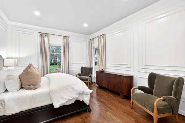 a bedroom with a bed couch and windows