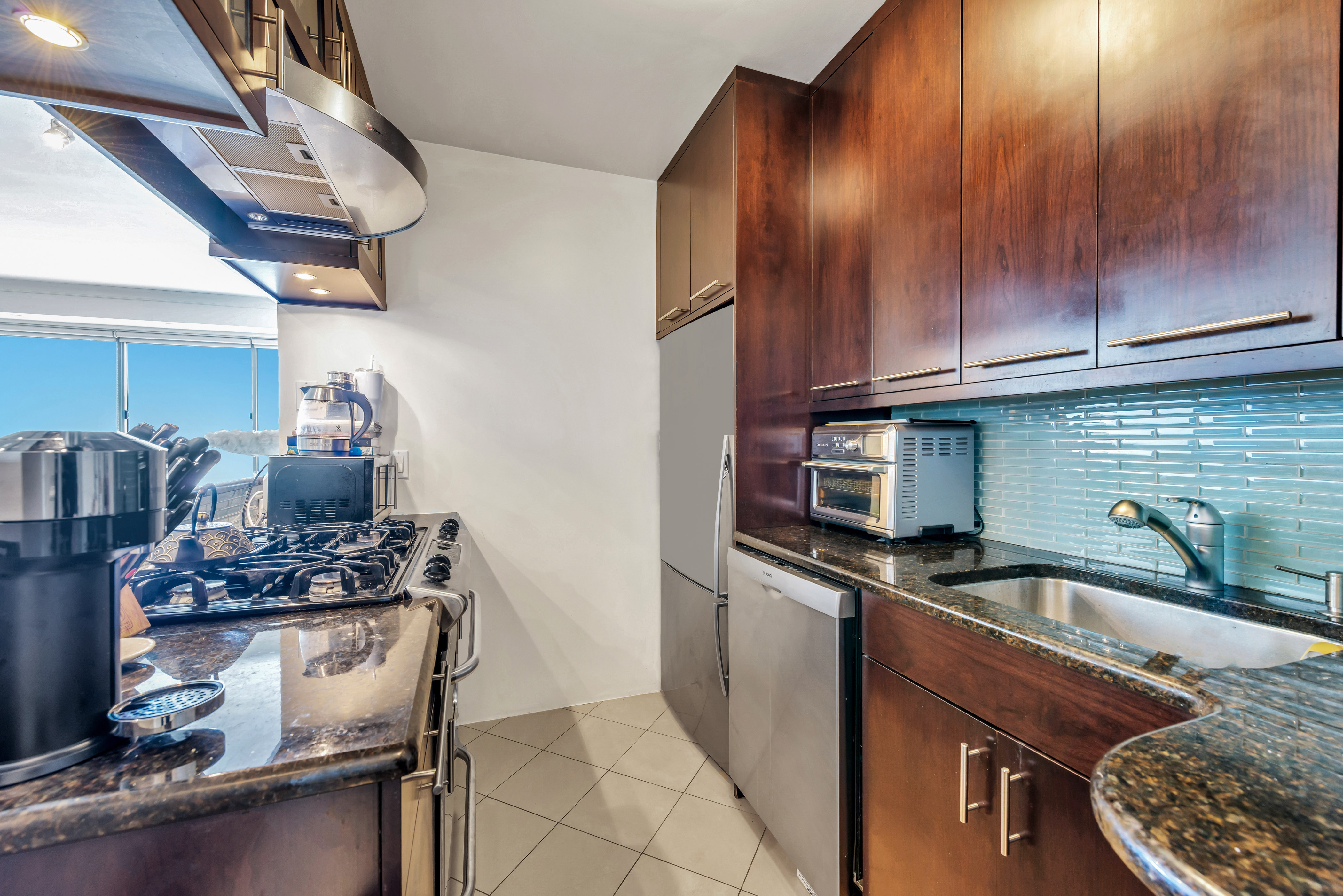 175 West 12th Street, Unit 12F Manhattan, NY 10011 - Photo 5 of 10 a kitchen with kitchen island granite countertop a sink stove and cabinets