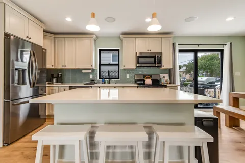 a kitchen with stainless steel appliances kitchen island granite countertop a stove a sink a oven a dining table and chairs