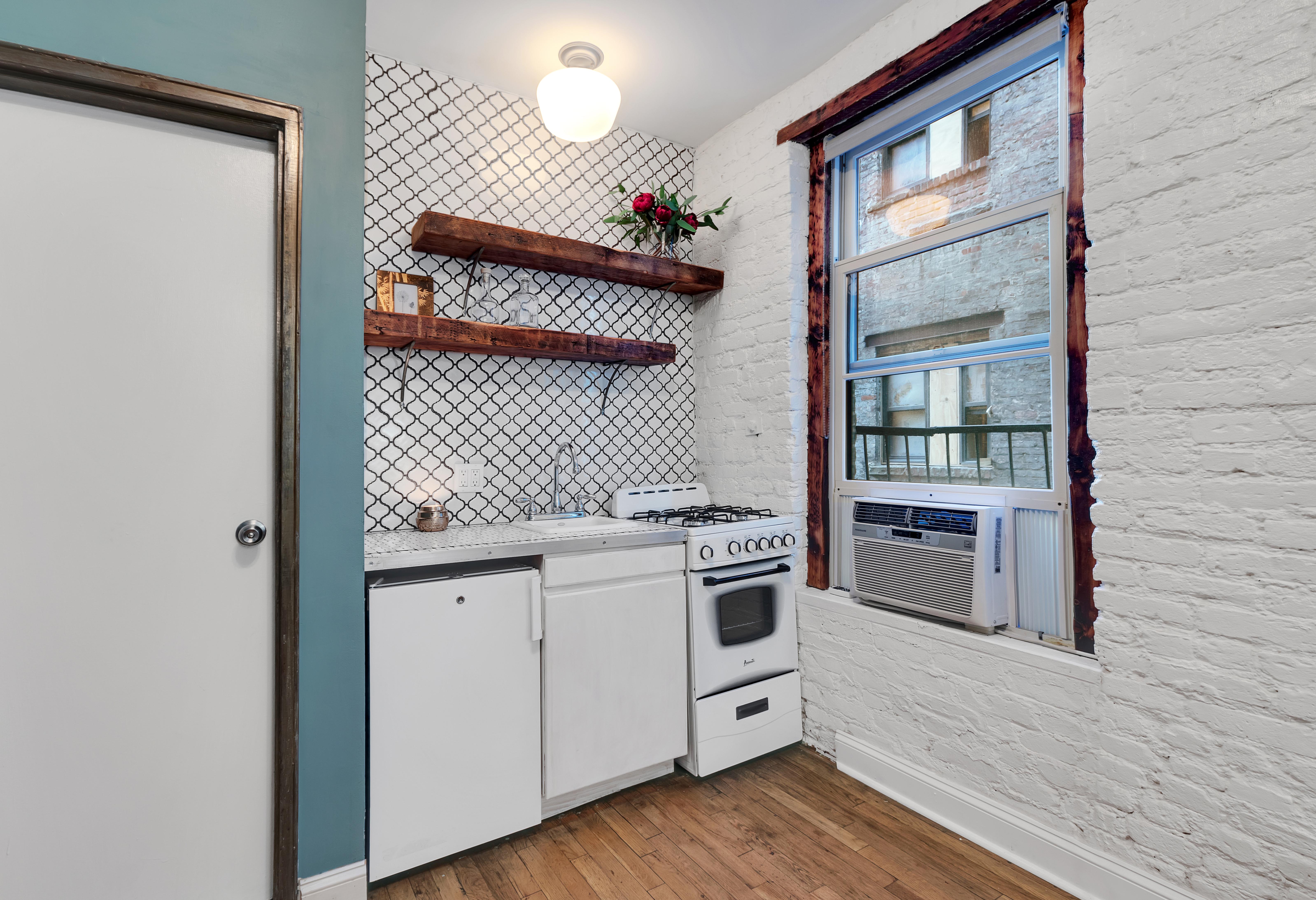57 Thompson Street, Unit 3F Manhattan, NY 10012 - Photo 2 of 7 a kitchen with granite countertop a stove and a wooden floor