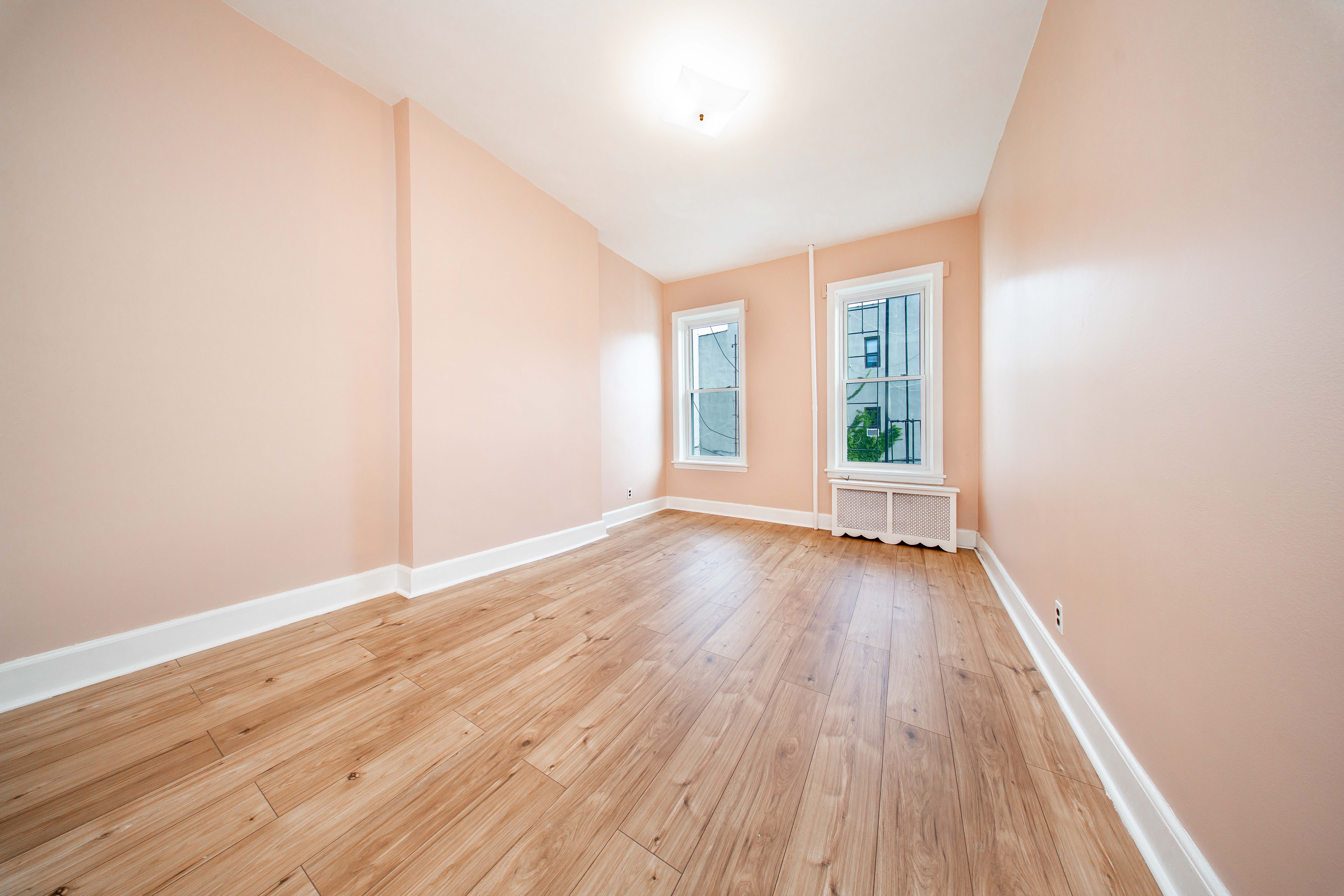 22-17 Astoria Boulevard, Unit 2W Queens, NY 11102 - Photo 9 of 10 an empty room with wooden floor and windows