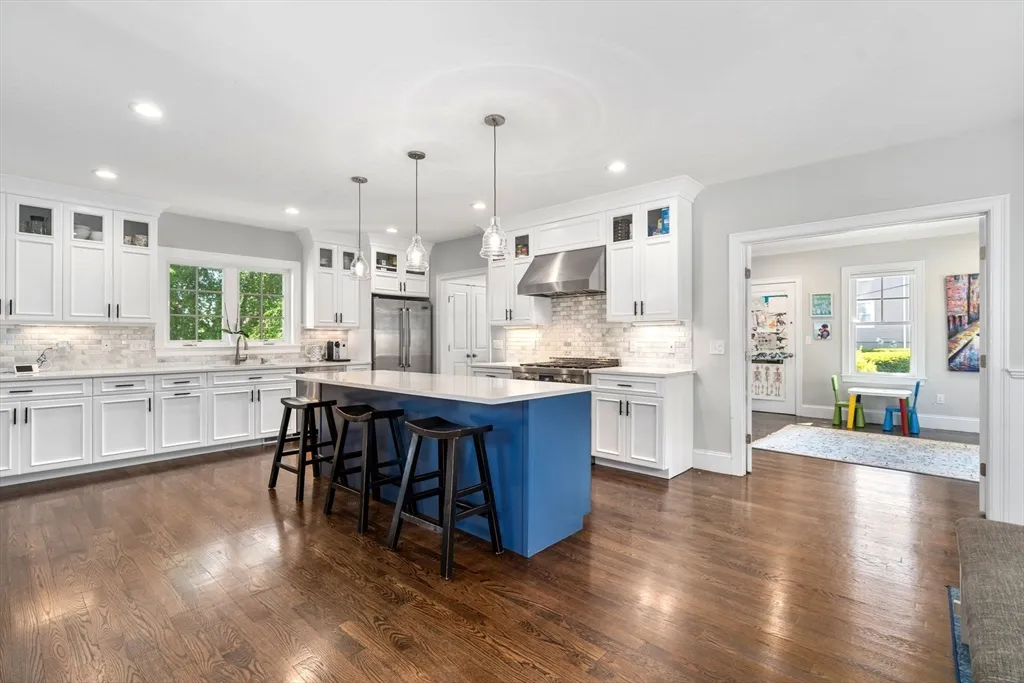 a kitchen with stainless steel appliances granite countertop a refrigerator a sink dishwasher a stove and white cabinets with wooden floor