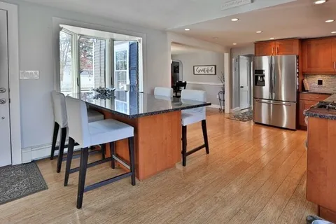 a kitchen with stainless steel appliances a dining table chairs stove refrigerator and cabinets