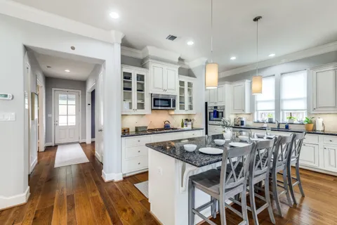a kitchen with stainless steel appliances granite countertop a stove top oven a sink dishwasher and a dining table with wooden floor