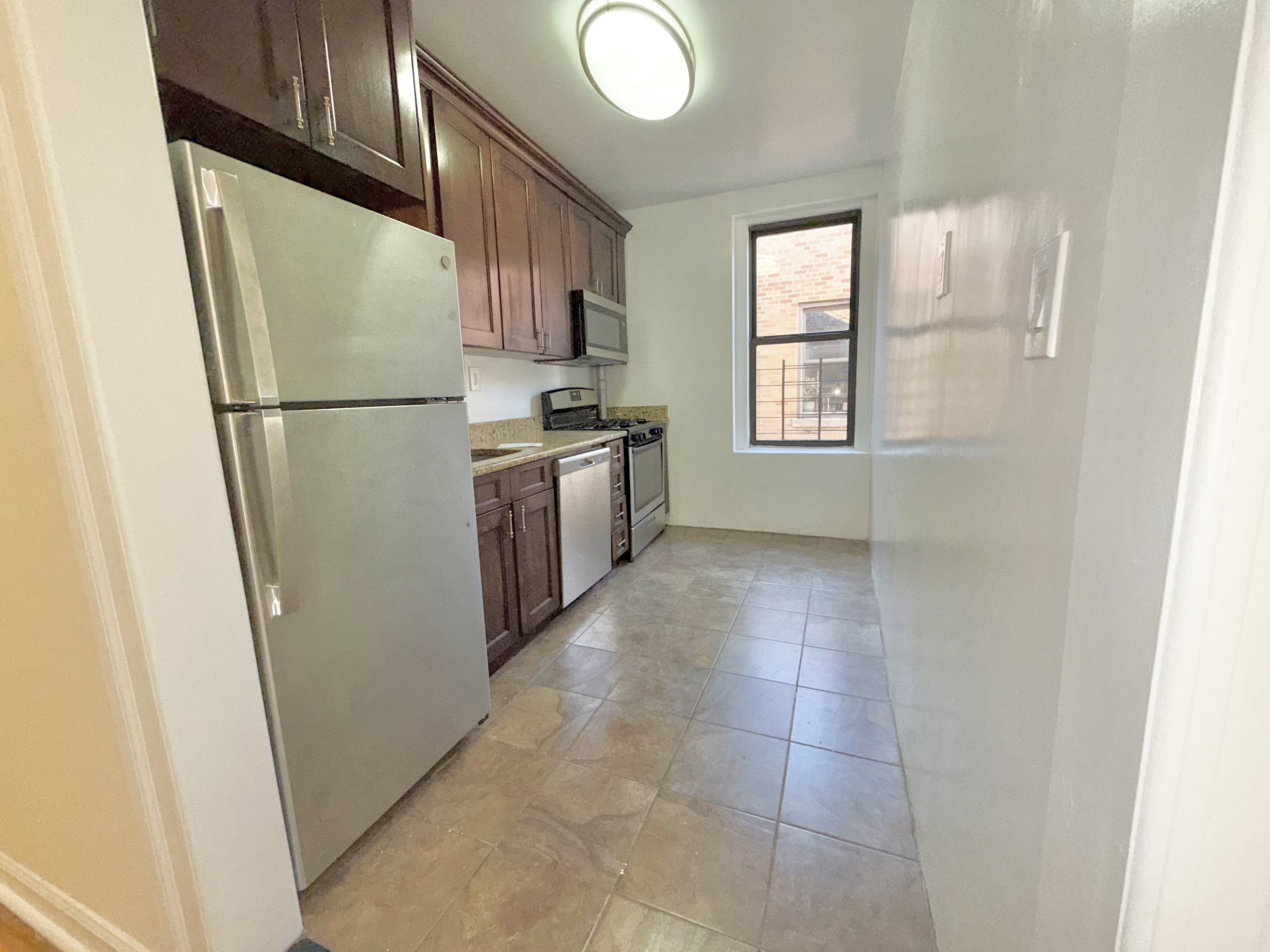 133 Seaman Avenue, Unit 3A Manhattan, NY 10034 - Photo 5 of 7 a kitchen with a refrigerator a stove top oven and cabinets