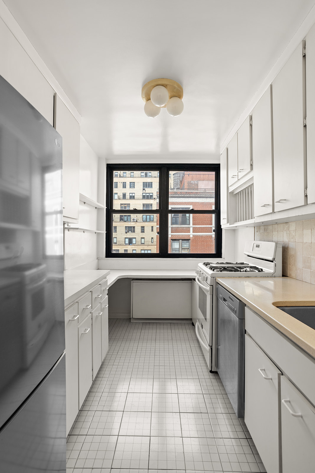 420 East 51st Street, Unit 10H Manhattan, NY 10022 - Photo 4 of 14 a kitchen with a stove a sink and a refrigerator