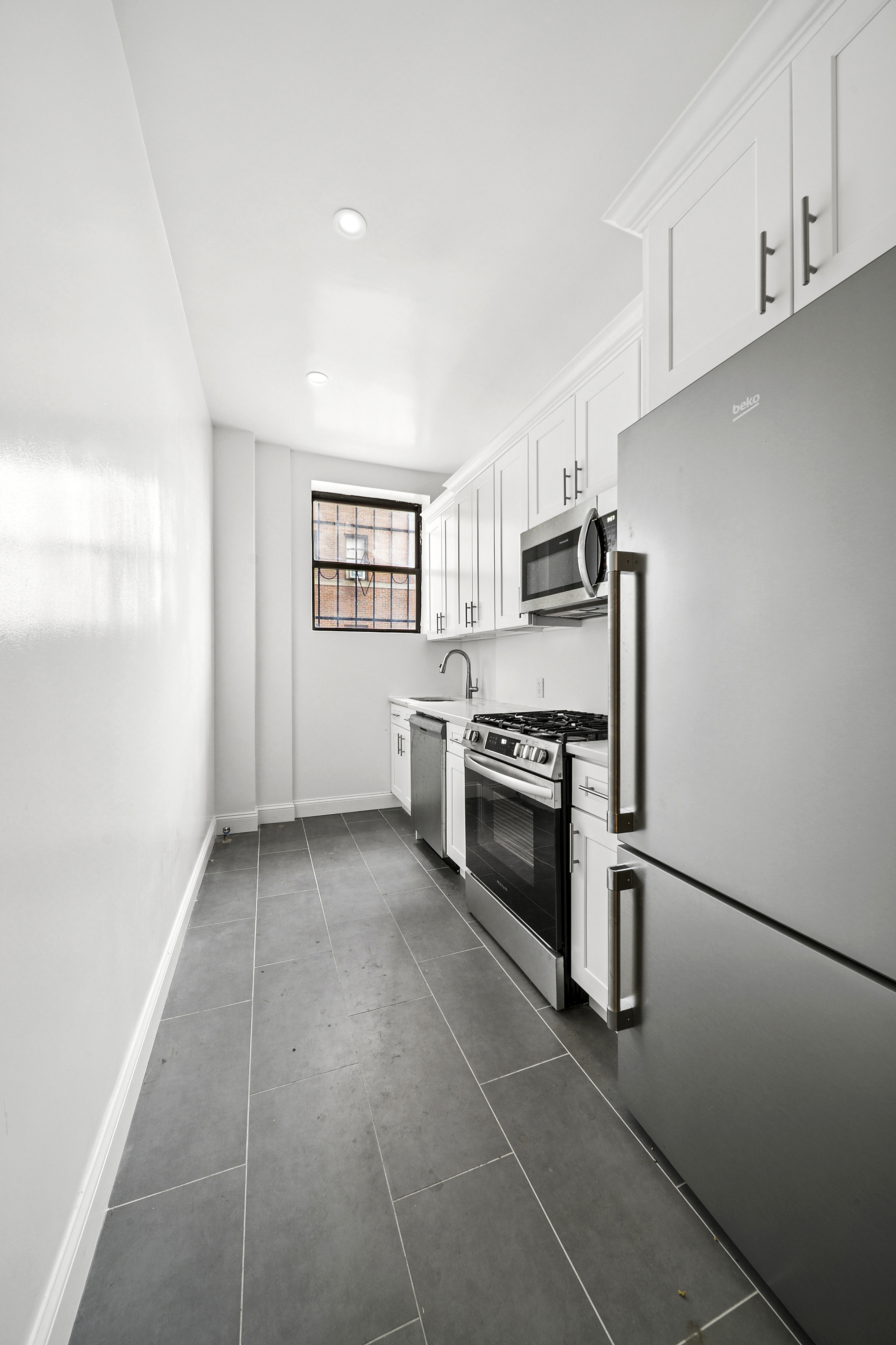159-00 Riverside Drive West, Unit 1L70 Manhattan, NY 10032 - Photo 4 of 17 a kitchen with a sink stainless steel appliances and cabinets