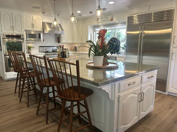 a kitchen with stainless steel appliances kitchen island granite countertop a table chairs and a refrigerator