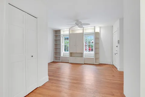 a view of an empty room with window and wooden floor