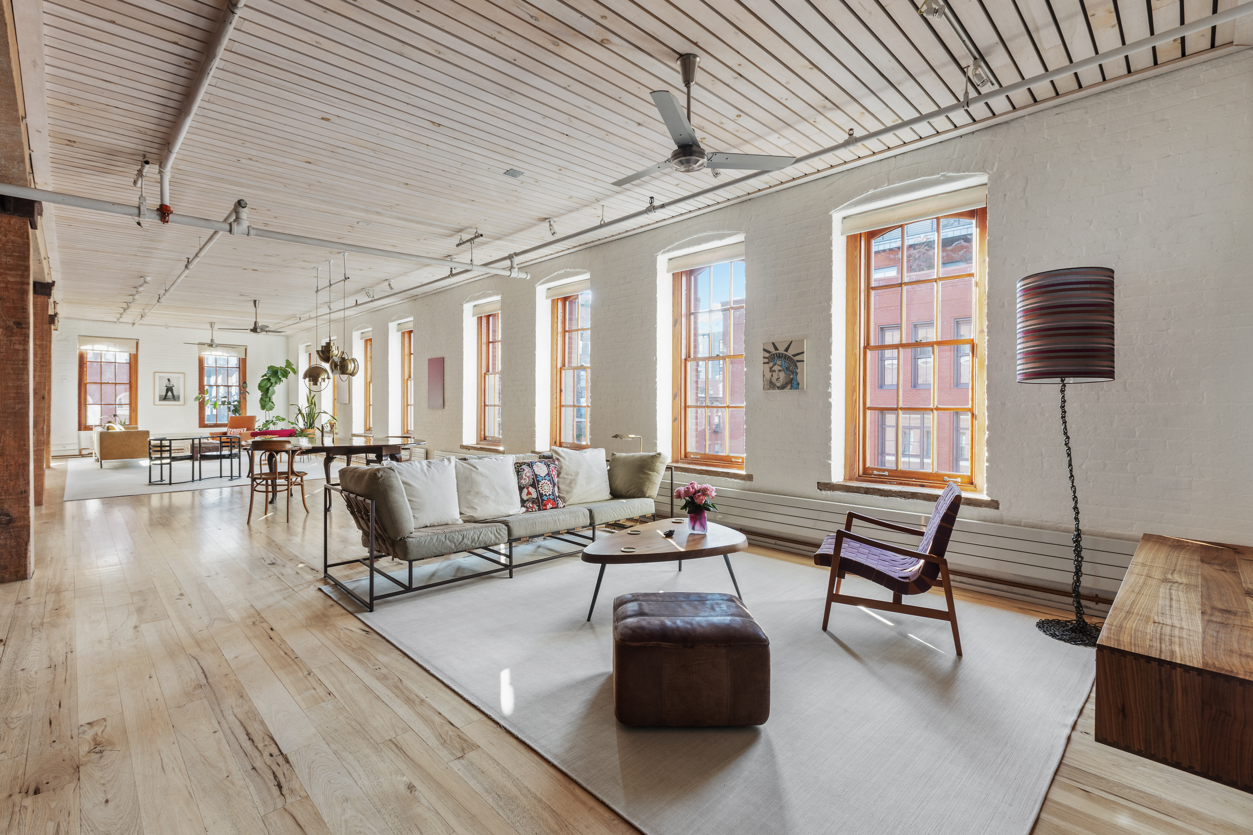 a living room with couches and a dining table with wooden floor
