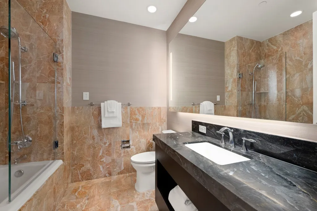 a bathroom with a granite countertop sink a toilet a mirror and shower