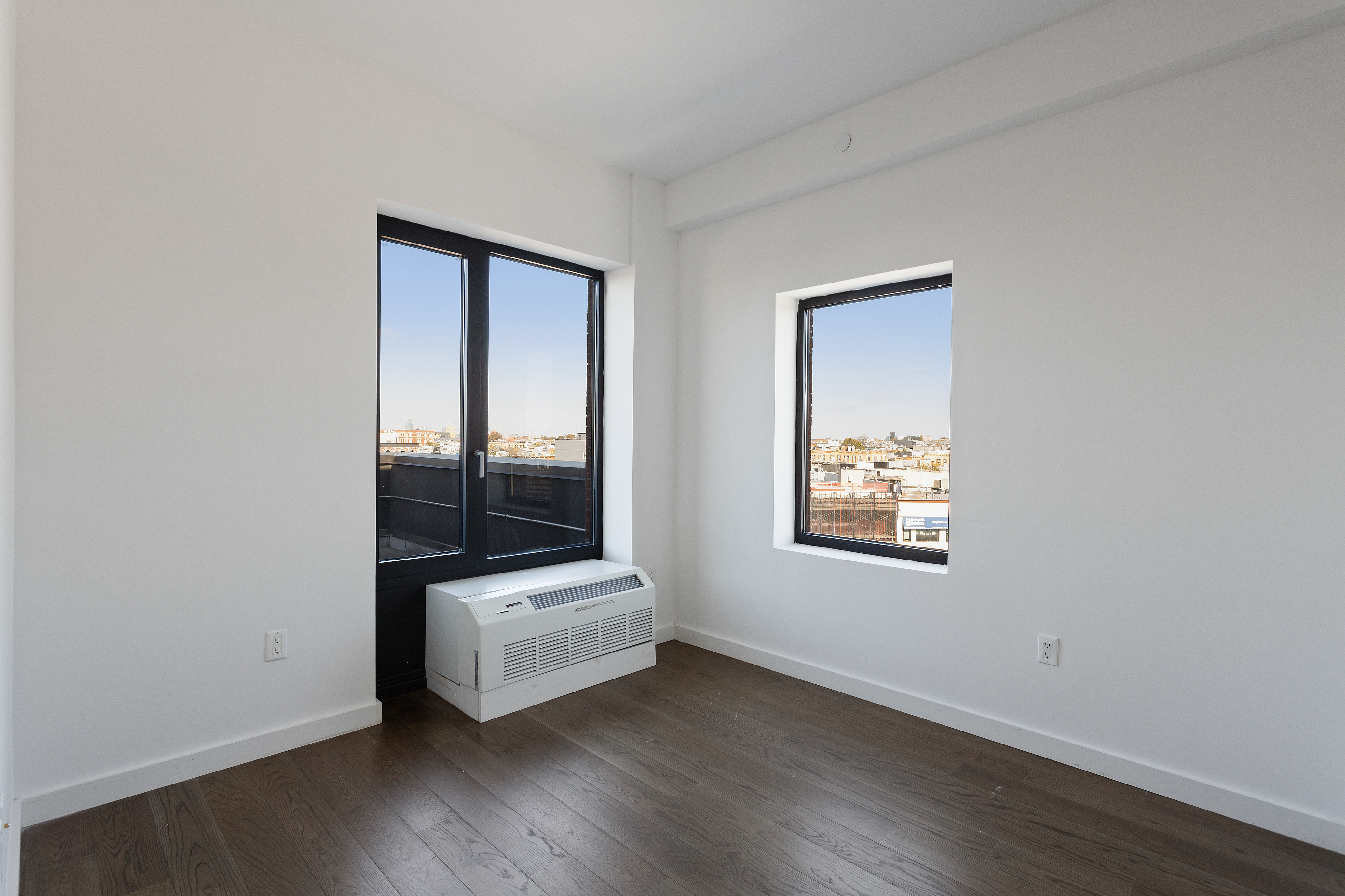 16-26 Madison Street, Unit PHA Queens, NY 11385 - Photo 8 of 16 an empty room with wooden floor and windows