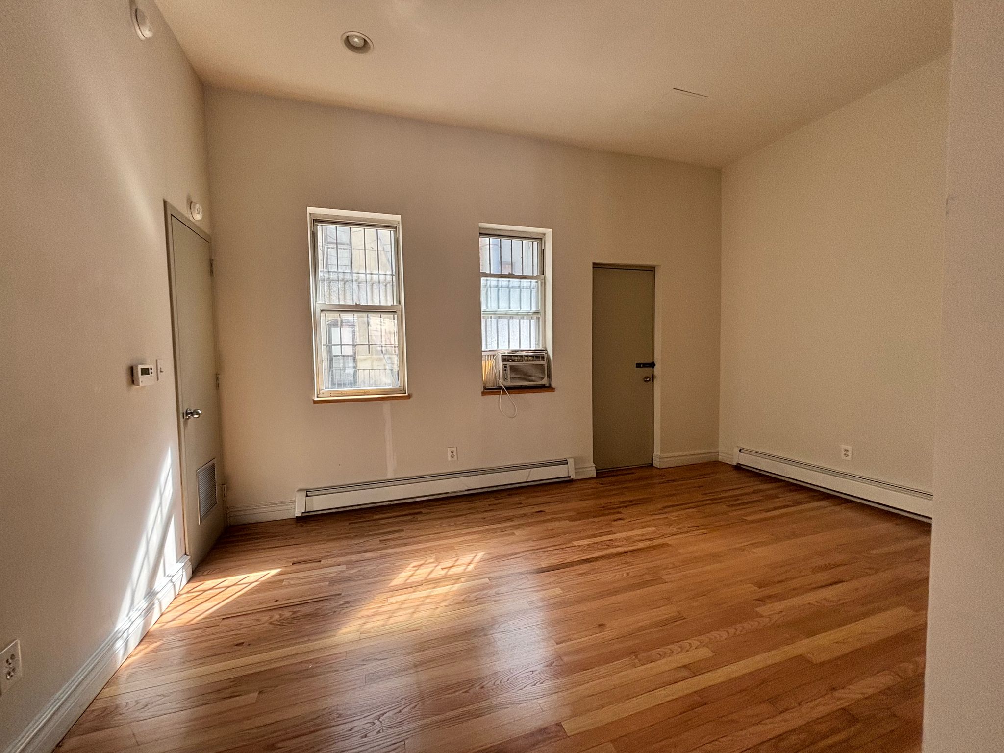 85 Division Street, Unit 4 Manhattan, NY 10002 - Photo 19 of 22 an empty room with wooden floor and windows