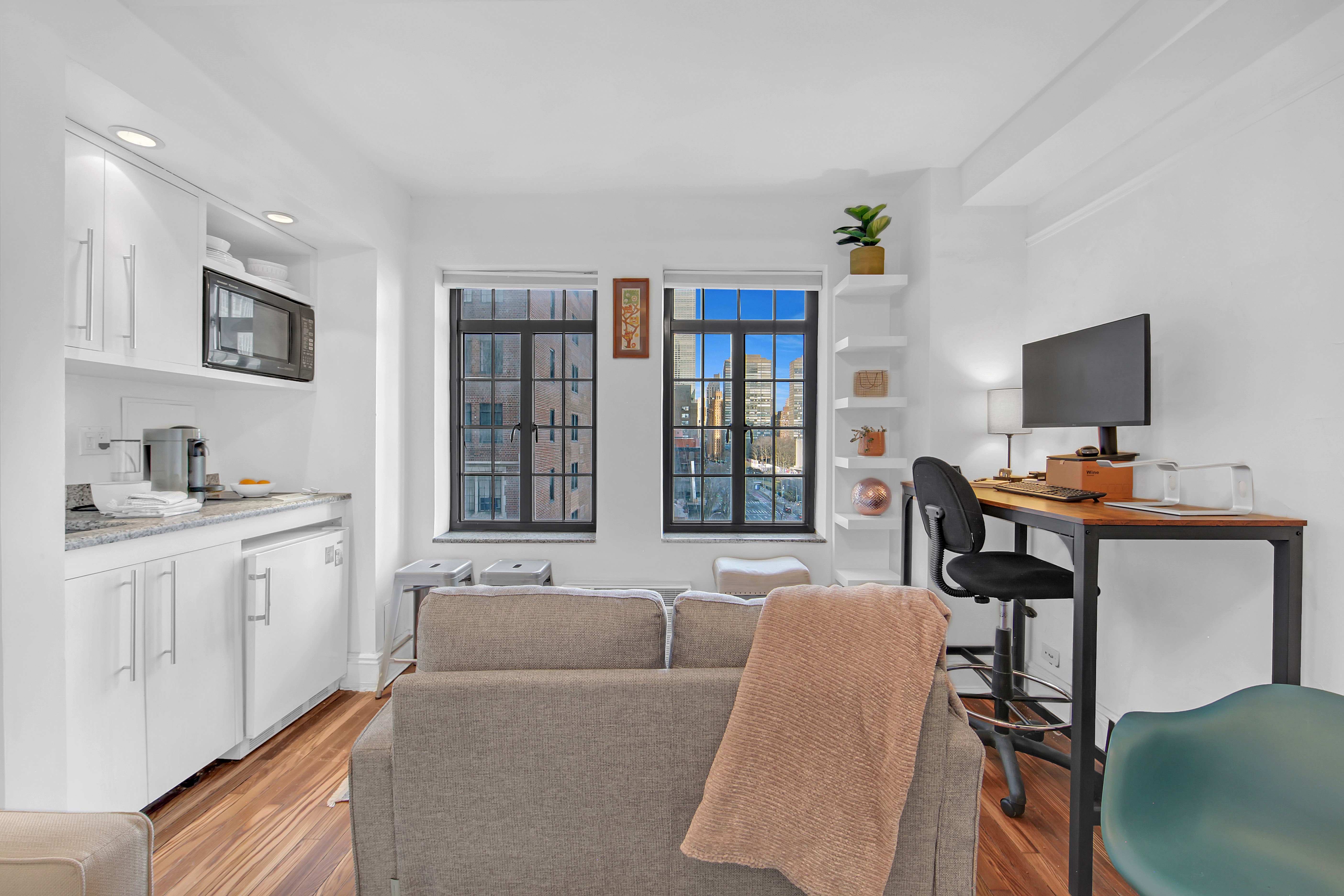 5 Tudor City Place, Unit 539 Manhattan, NY 10017 - Photo 3 of 12 a living room with furniture and a flat screen tv