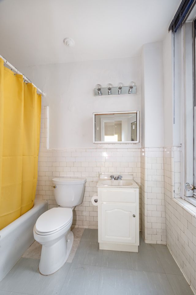 325 West 45th Street, Unit 108 Manhattan, NY 10036 - Photo 6 of 12 a bathroom with a white toilet sitting next to a bathroom sink and a tub