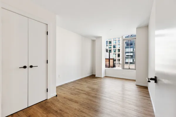 a view of an empty room with wooden floor and a window